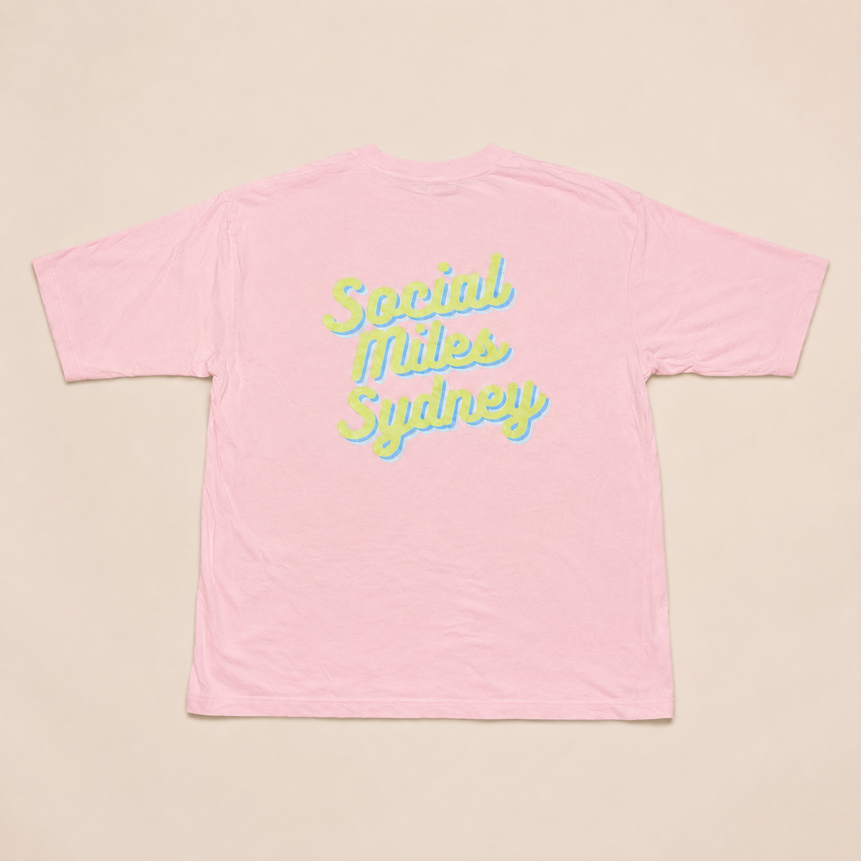Back view of the pink Social Miles Sydney oversized tee with the large yellow-and-blue retro Social Miles Sydney script.