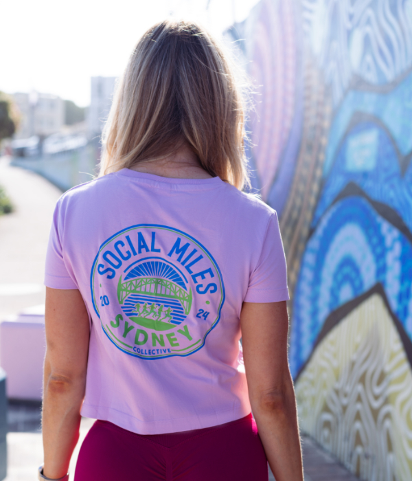 Member wearing the pink cropped Social Miles Sydney club tee, back view with the circular Sydney crest.