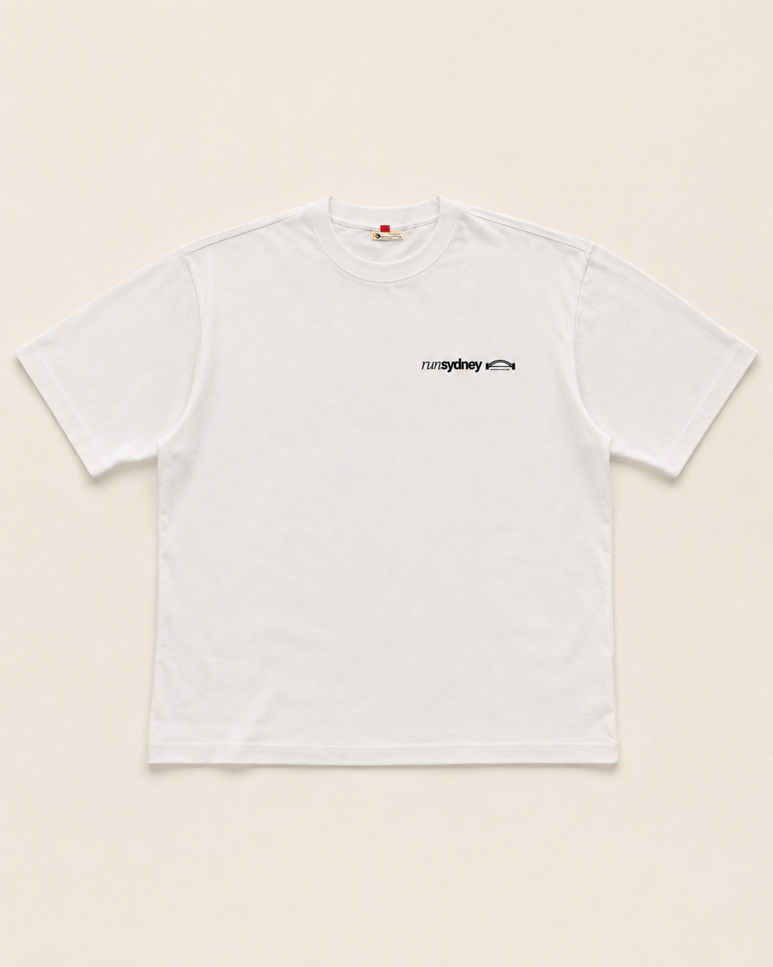 Front view of the white runSydney oversized Social Miles Sydney tee with the runSydney chest mark.