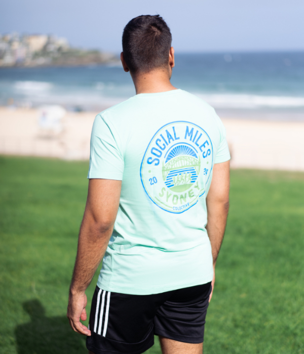 Member wearing the mint Social Miles Sydney club tee, back view with the circular Sydney crest.