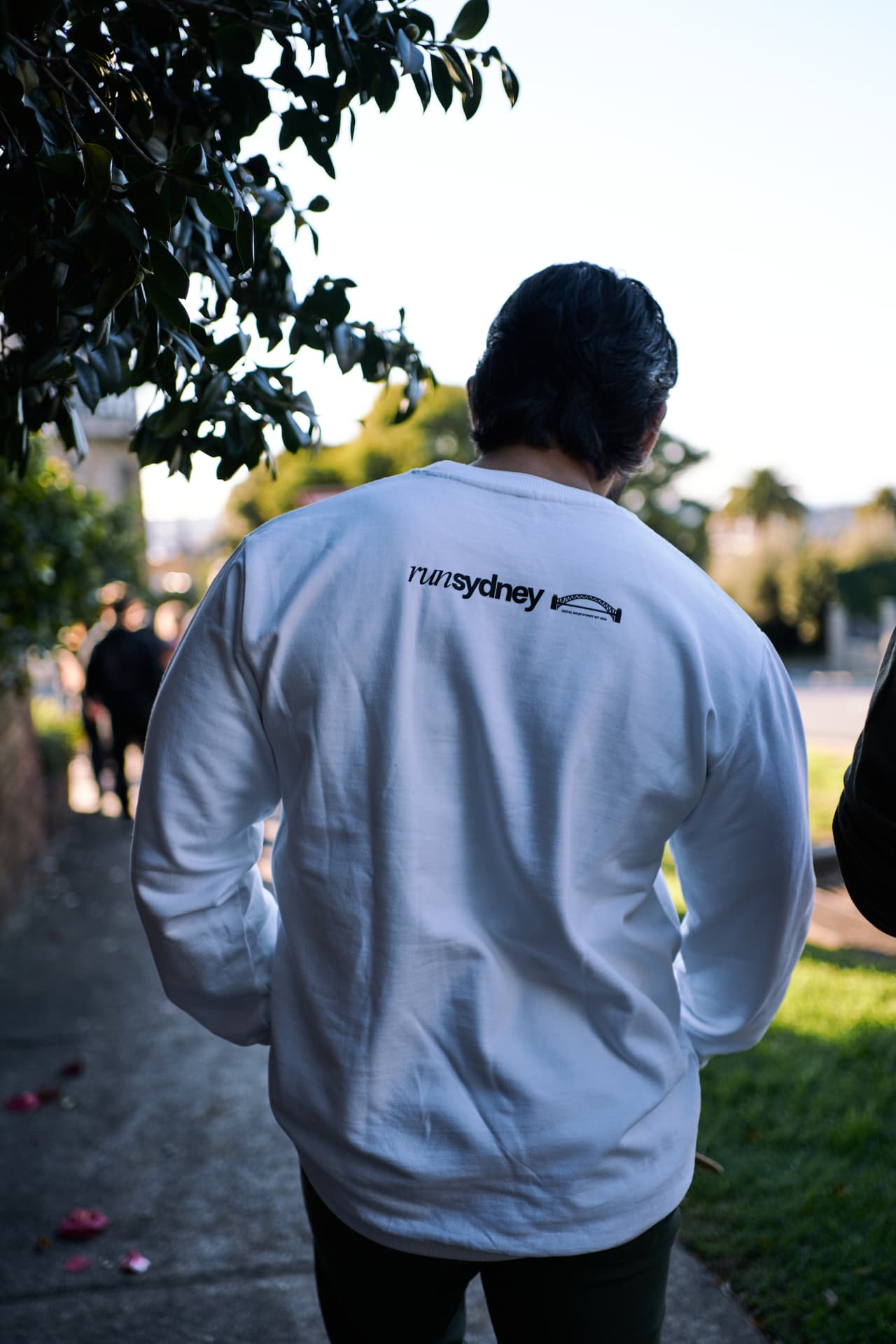 Back of a white runSydney long sleeve top showing the runSydney bridge wordmark.
