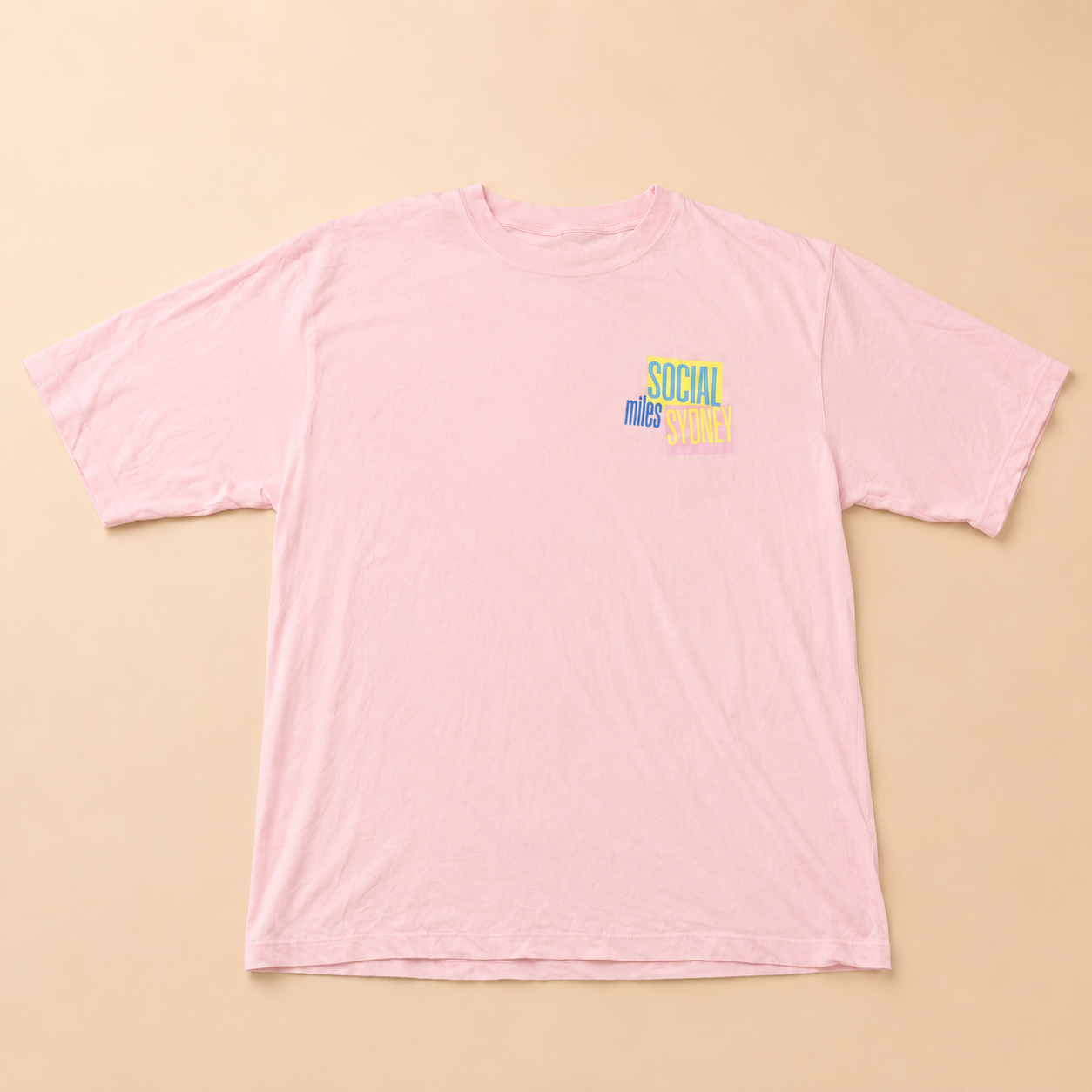 Front view of the pink Social Miles Sydney oversized tee with the yellow-and-blue Social Miles chest graphic.