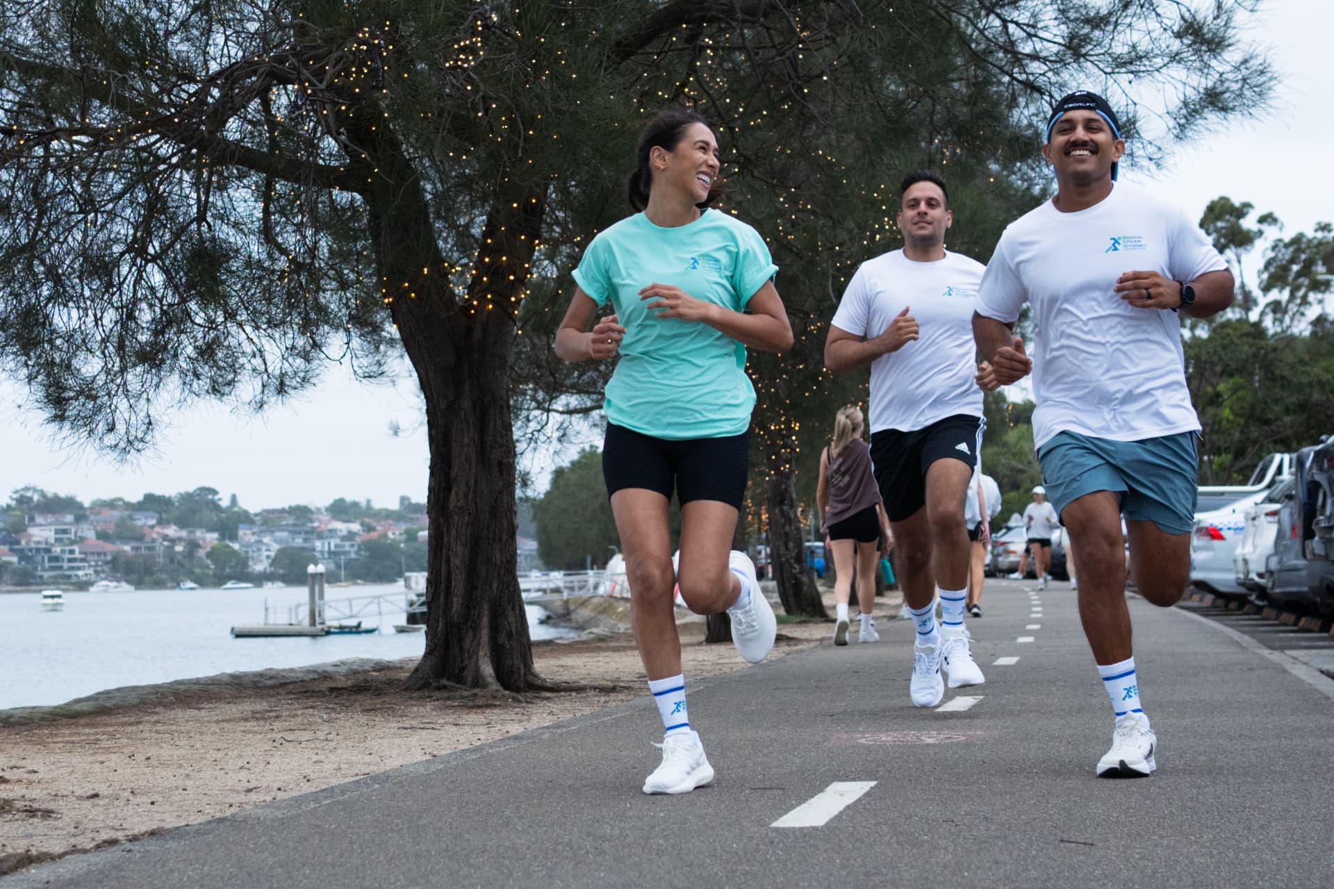 Social Miles Sydney runners smiling together on the waterfront path
